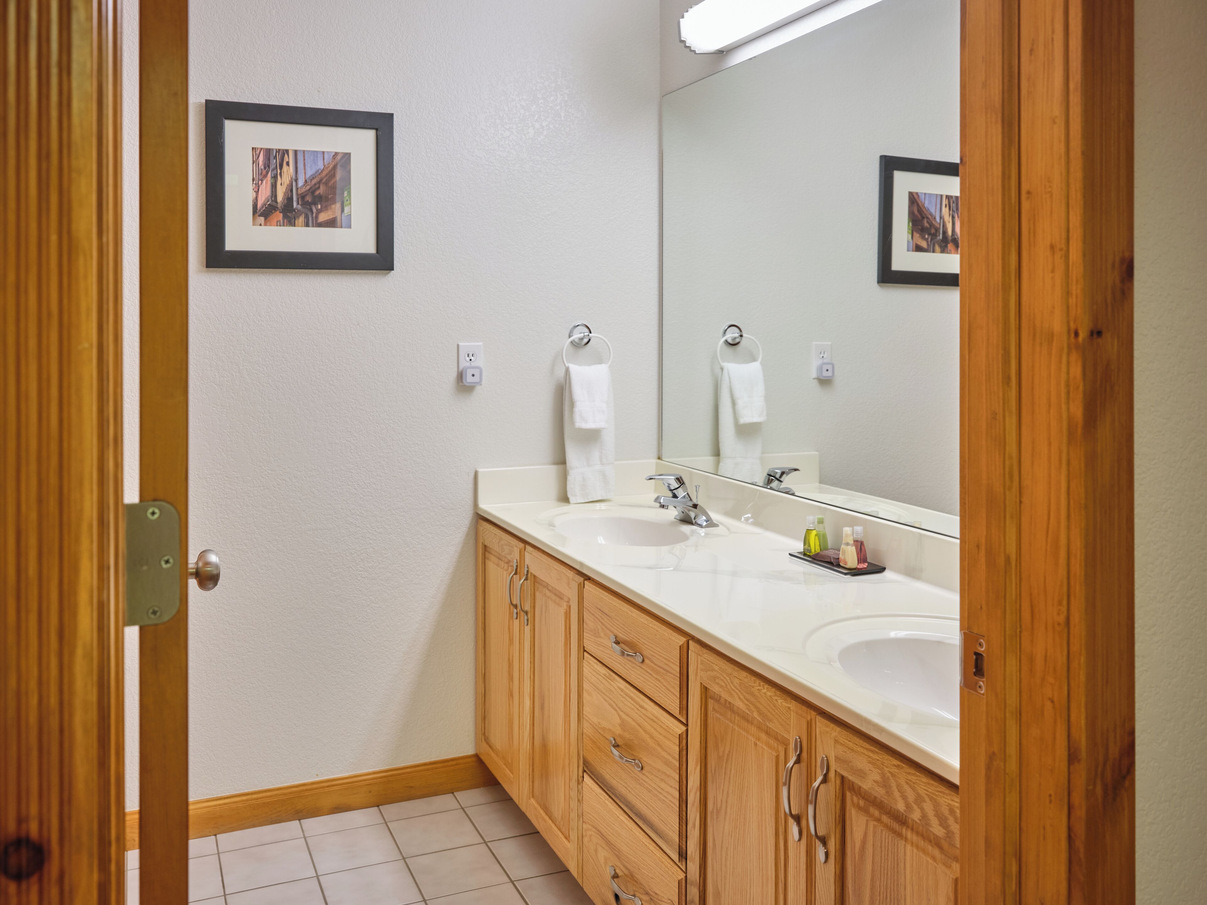 Une salle de bain avec des meubles en bois, un lavabo blanc et un grand miroir.