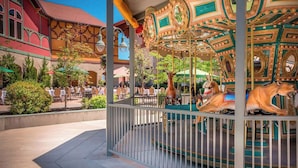 A carousel with ornate golden and teal decorations, surrounded by a metal fence. - Zermatt Utah Resort & Spa Trademark Collection by Wyndham (Midway)