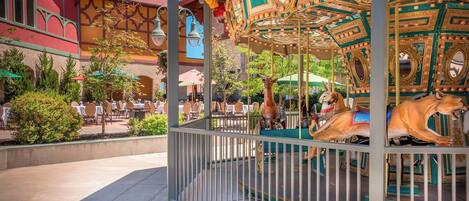A carousel with ornate golden and teal decorations, surrounded by a metal fence.