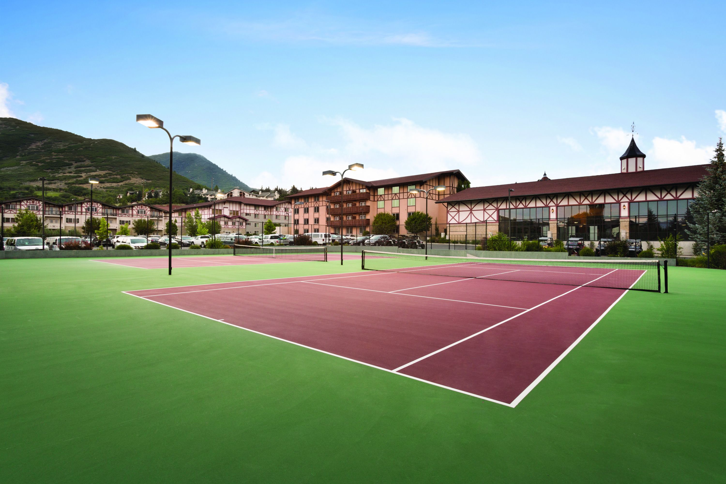 Una cancha de tenis con una red, rodeada de edificios de estilo arquitectónico tradicional.