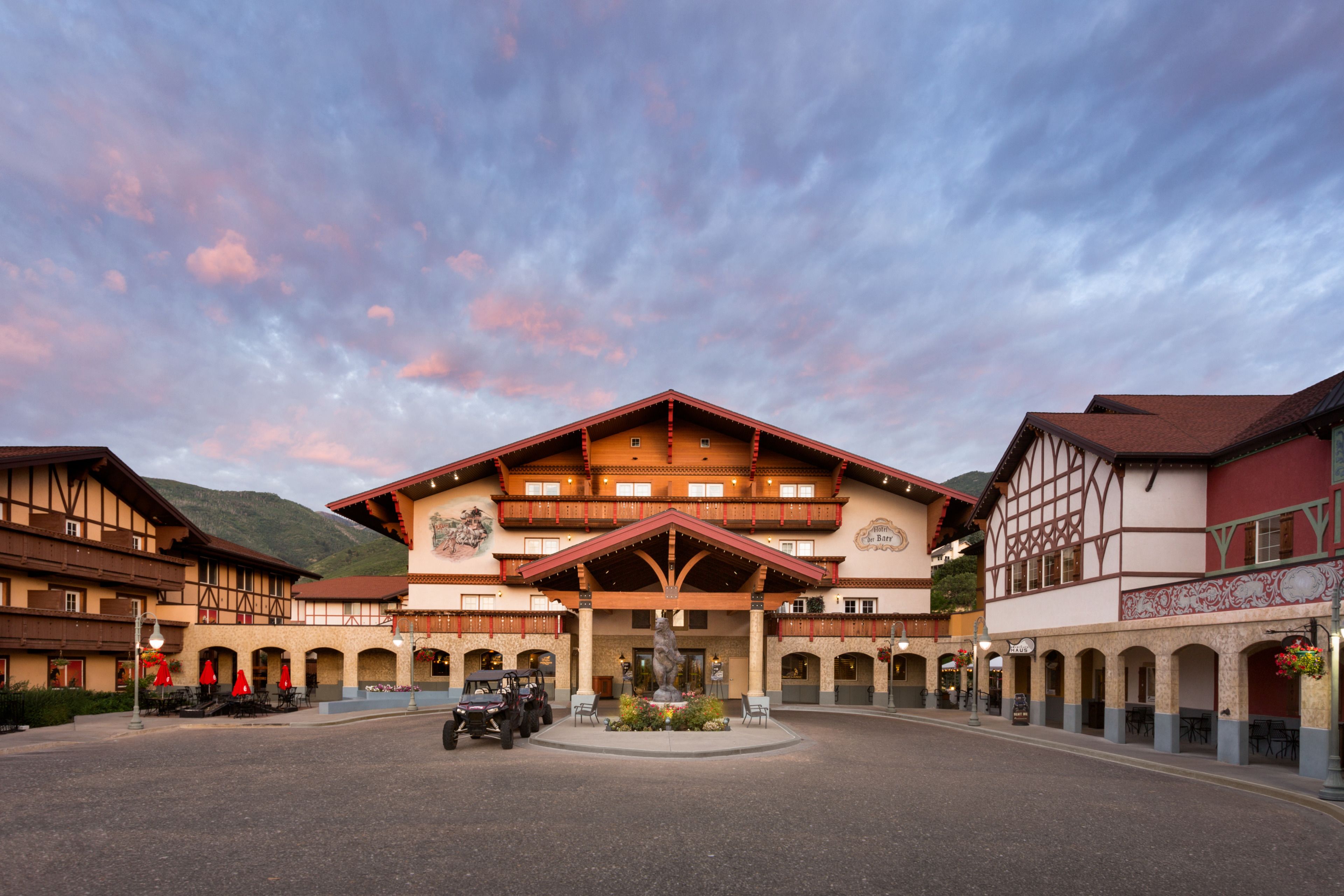 Un bâtiment de style alpin traditionnel, doté d’une entrée centrale, de plusieurs balcons et d’une cour avec des espaces de repos en plein air.