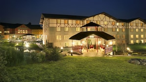A large hotel with a covered outdoor dining area, a pond, and well-maintained lawns. - Zermatt Utah Resort & Spa Trademark Collection by Wyndham (Midway)
