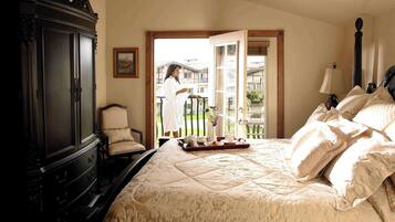 A bedroom with a large bed, a dark wooden wardrobe, a chair, and a balcony with a view.