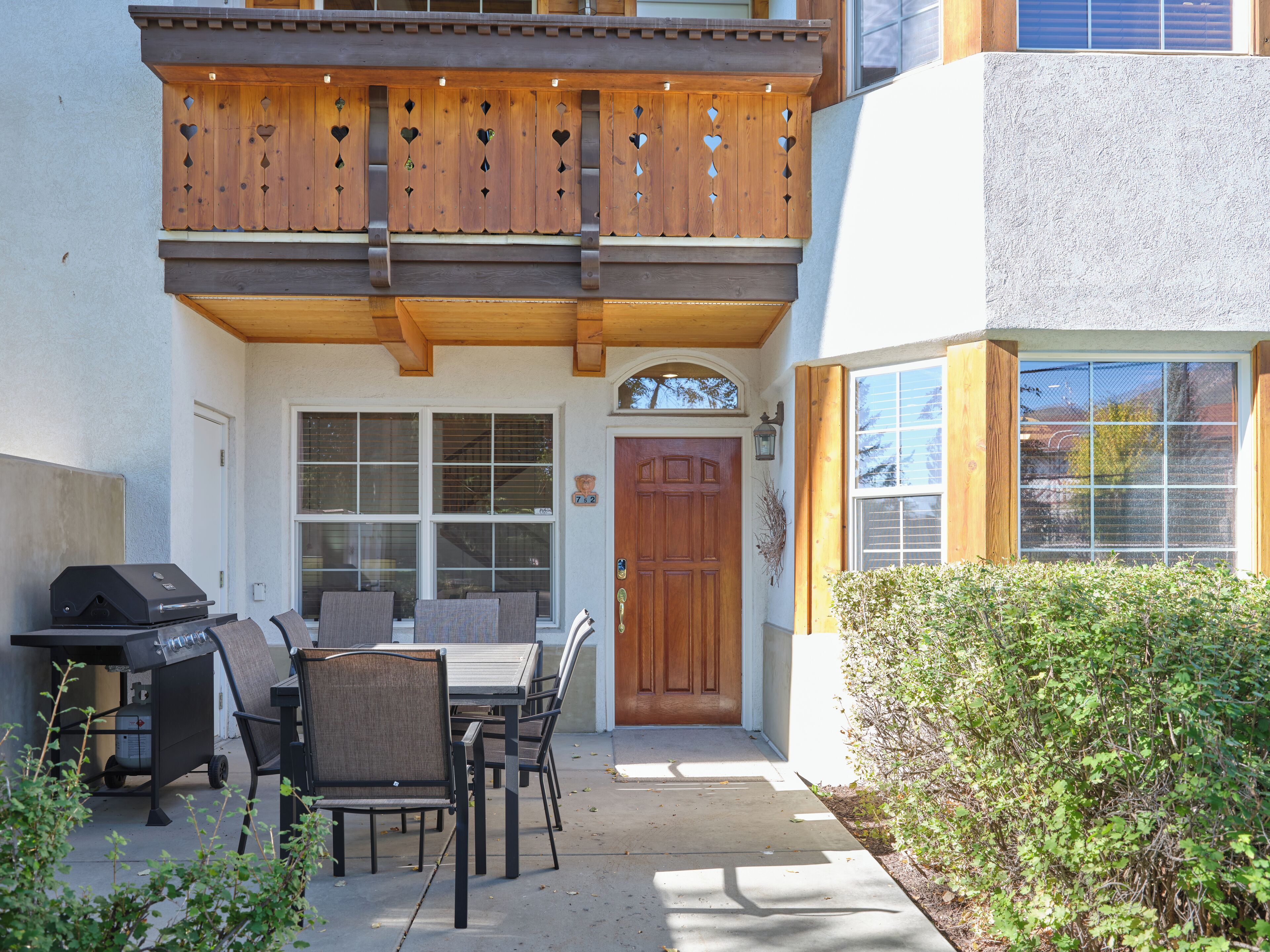 Eine Terrasse mit Grill, Sitzgelegenheiten im Freien und einem Holzbalkon.