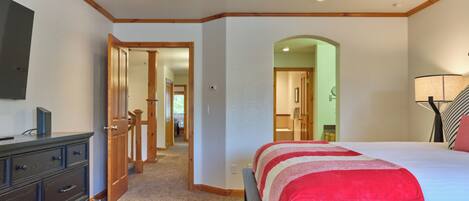 Une chambre à coucher avec un lit, une commode et un téléviseur fixé au mur.
