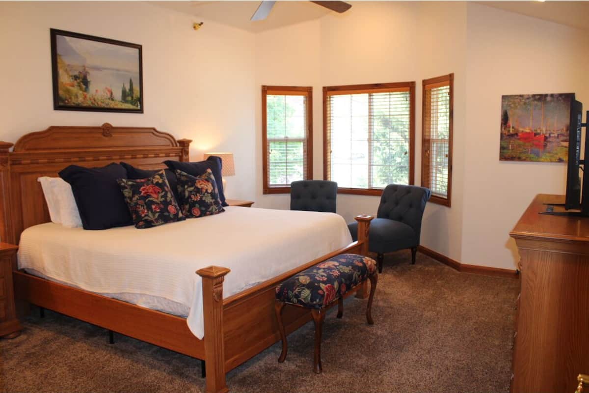 A bedroom with a wooden bed, a bench, a chair, and a desk.