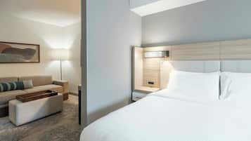 Ein modernes Hotelzimmer mit einem großen Bett, einer Couch, einem kleinen Tisch und einem Nachttisch mit Lampe.