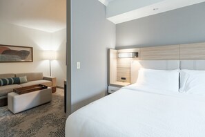 Ein Hotelzimmer mit Bett, Nachttisch, Lampe, Sofa und einem Bild an der Wand.