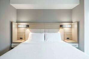 A modern hotel room with a large bed, two bedside tables, and a headboard with integrated lighting. - SpringHill Suites Charlotte Lake Norman/Mooresville (Mooresville)