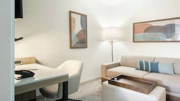 Una habitación de hotel moderna con escritorio, silla, sofá y lámpara.