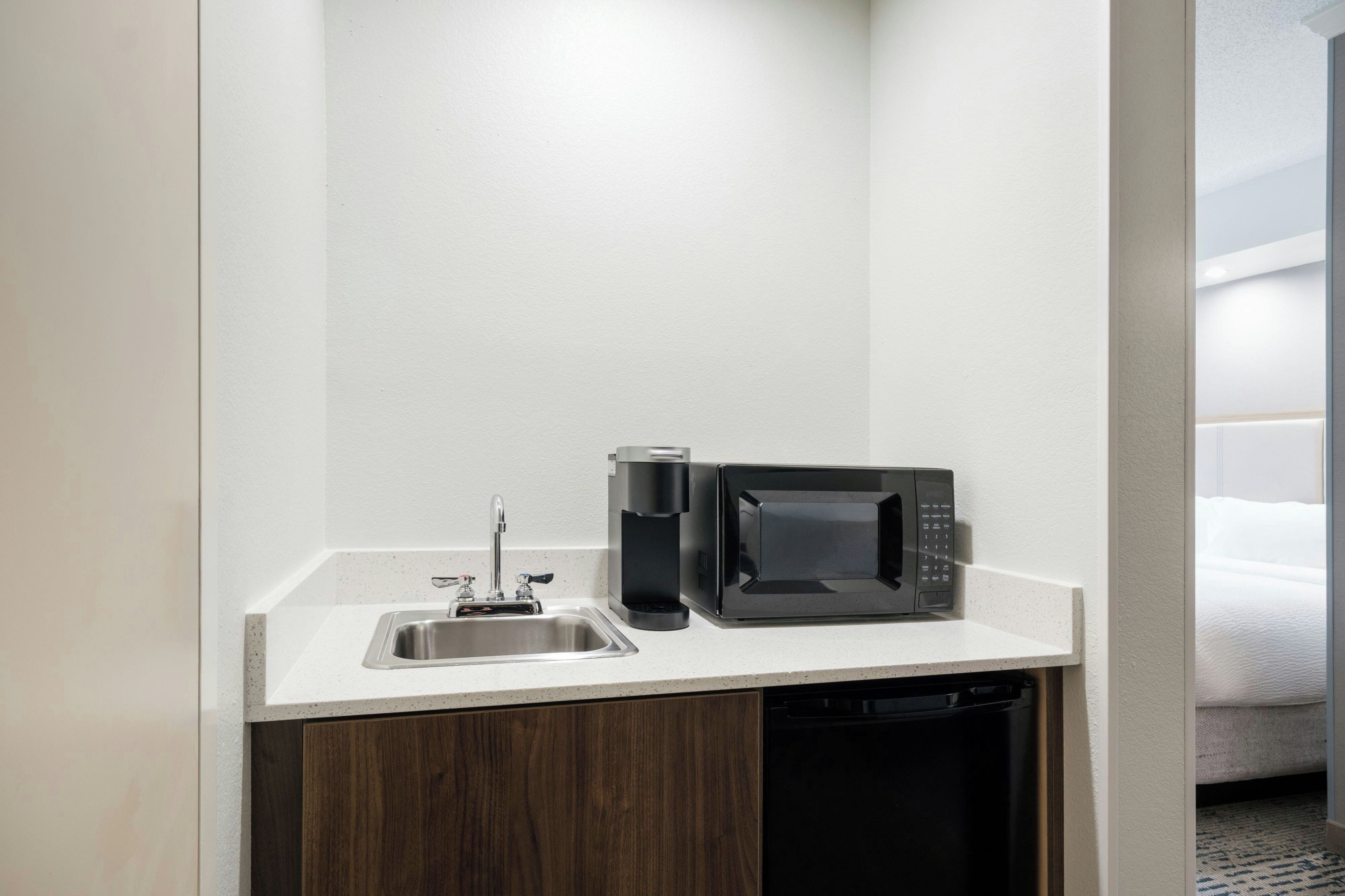 A compact kitchenette with a stainless steel sink, a coffee maker, and a microwave.