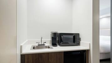 A compact kitchenette with a stainless steel sink, a coffee maker, and a microwave.