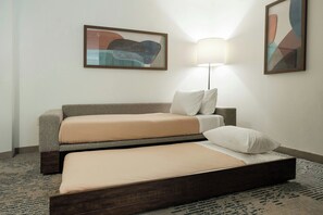 Habitación de hotel con sofá cama, una cama separada, una lámpara y arte abstracto en las paredes.