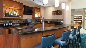 A bar area with a counter, bar stools, and a variety of bottles and glasses.