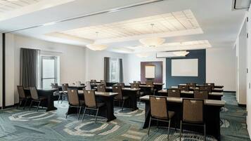 A conference room with tables and chairs, a whiteboard, and a projector screen.