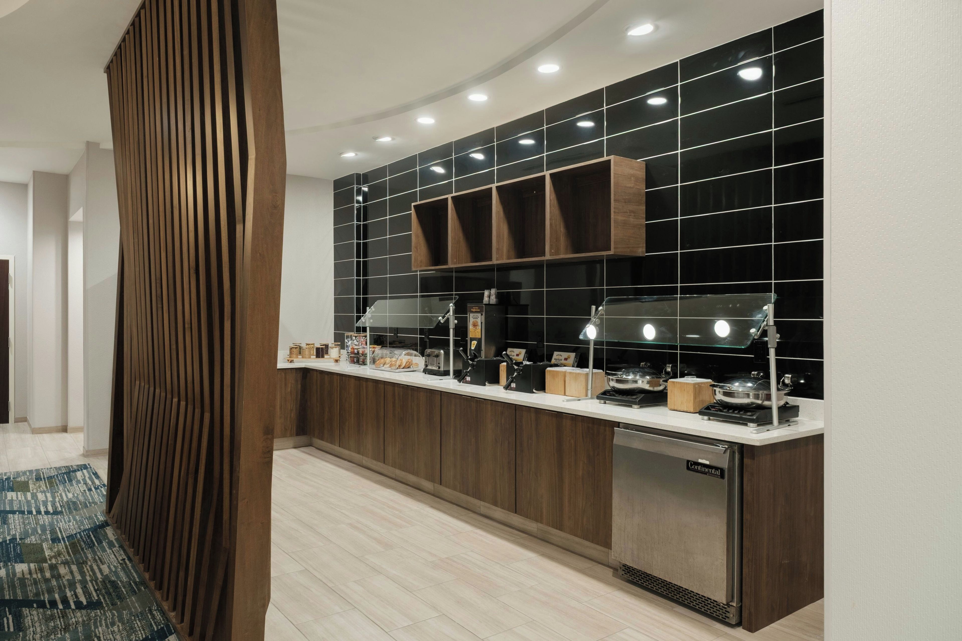 A modern kitchen with a built-in stove, a sink, and a countertop with various appliances and storage cabinets.
