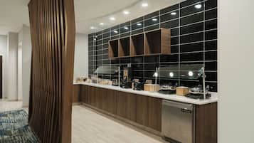 A modern kitchen with a built-in stove, a sink, and a countertop with various appliances and storage cabinets.