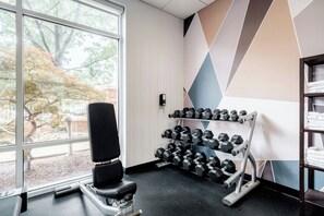 Ein Fitnessraum mit Rudergerät, Hanteln und einem Handtuchhalter.