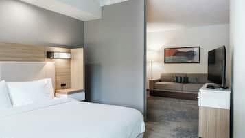A hotel room with a bed, a desk, a chair, a television, and a painting on the wall.