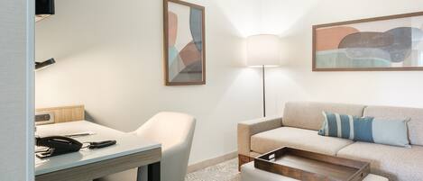Una habitación de hotel moderna con escritorio, silla, sofá y lámpara.