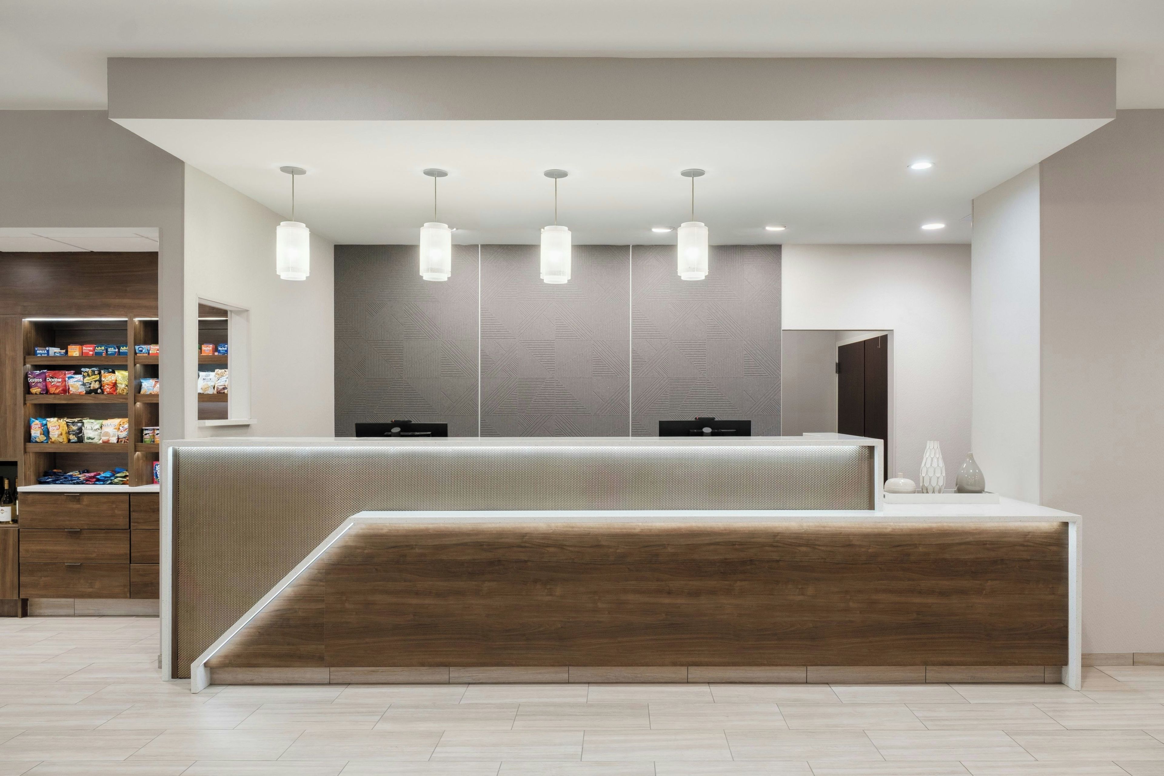 A reception area with a wooden reception desk, a patterned wall, and pendant lighting.