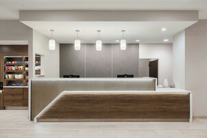 Una zona de recepción con un mostrador de madera, un muro estampado e iluminación colgante.