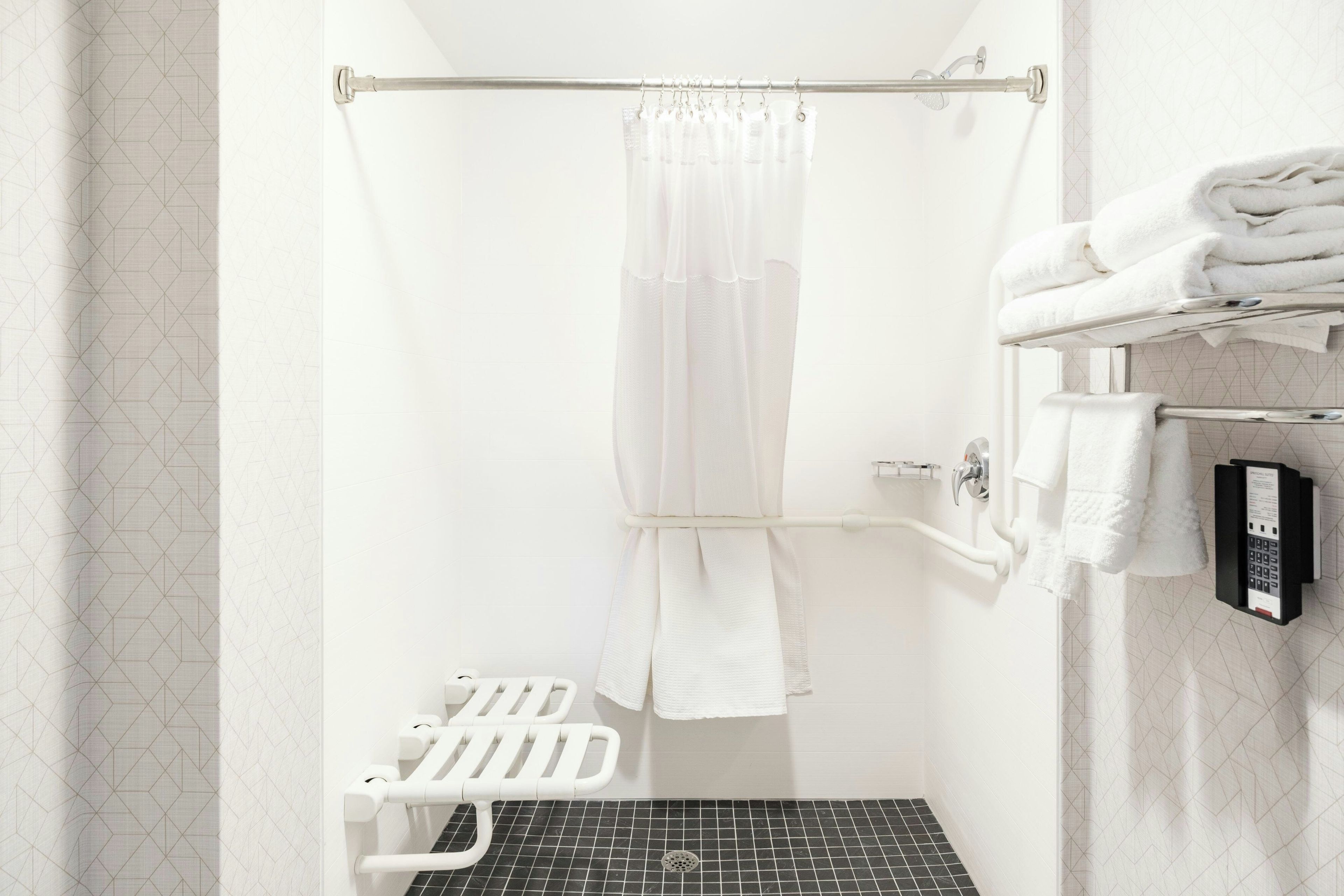 Un baño con ducha, toallero, inodoro y dispensador de toallas.
