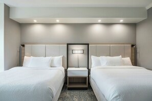 Une chambre d’hôtel avec deux lits, une table de chevet et un luminaire fixé au mur.