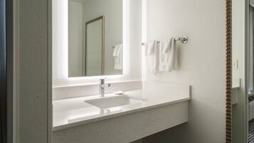 A bathroom with a white sink, a mirror, and two towels hanging on a towel rack.