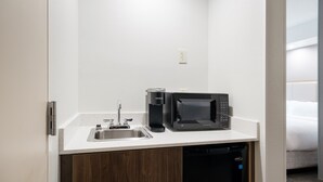 Eine kompakte Küchenzeile mit Spüle, Kaffeemaschine, Mikrowelle und Geschirrspüler.