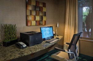 Un mostrador de recepción de hotel con una computadora de escritorio, un teléfono y una impresora.