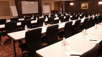 Un salón de conferencias con filas de mesas y sillas, equipado con botellas de agua y tarjetas de identificación.