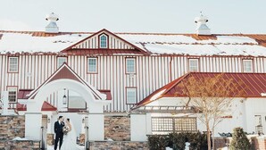 Un grand bâtiment à deux étages, doté d’un toit rouge et de murs blancs, qui se distingue par une entrée en arc surélevé et des fondations en pierre.