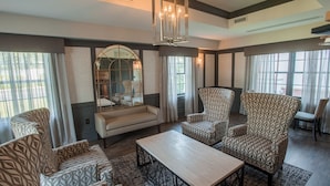 Une pièce spacieuse, avec des fauteuils à motifs, un canapé, une table basse en bois et un grand miroir.