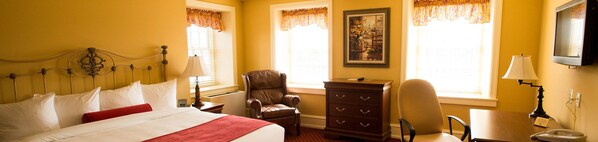 A hotel room with a bed, a chair, a dresser, and a desk.
