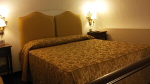 Quarto de hotel com cama, duas luminárias de cabeceira e mesa de cabeceira.