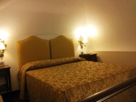 Una habitación de hotel con una cama grande, dos lámparas de noche y una mesita de noche.