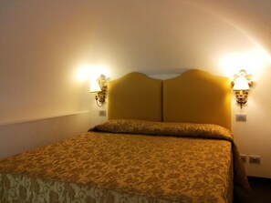 A hotel room with a double bed, two wall-mounted lamps, and a patterned bedspread. - Minotel Lanzillotta (Alberobello)