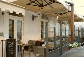 Un área de comedor al aire libre con mesas y sillas, un cartel de menú y un letrero que dice 'La Dolce Vita Ristorante'.