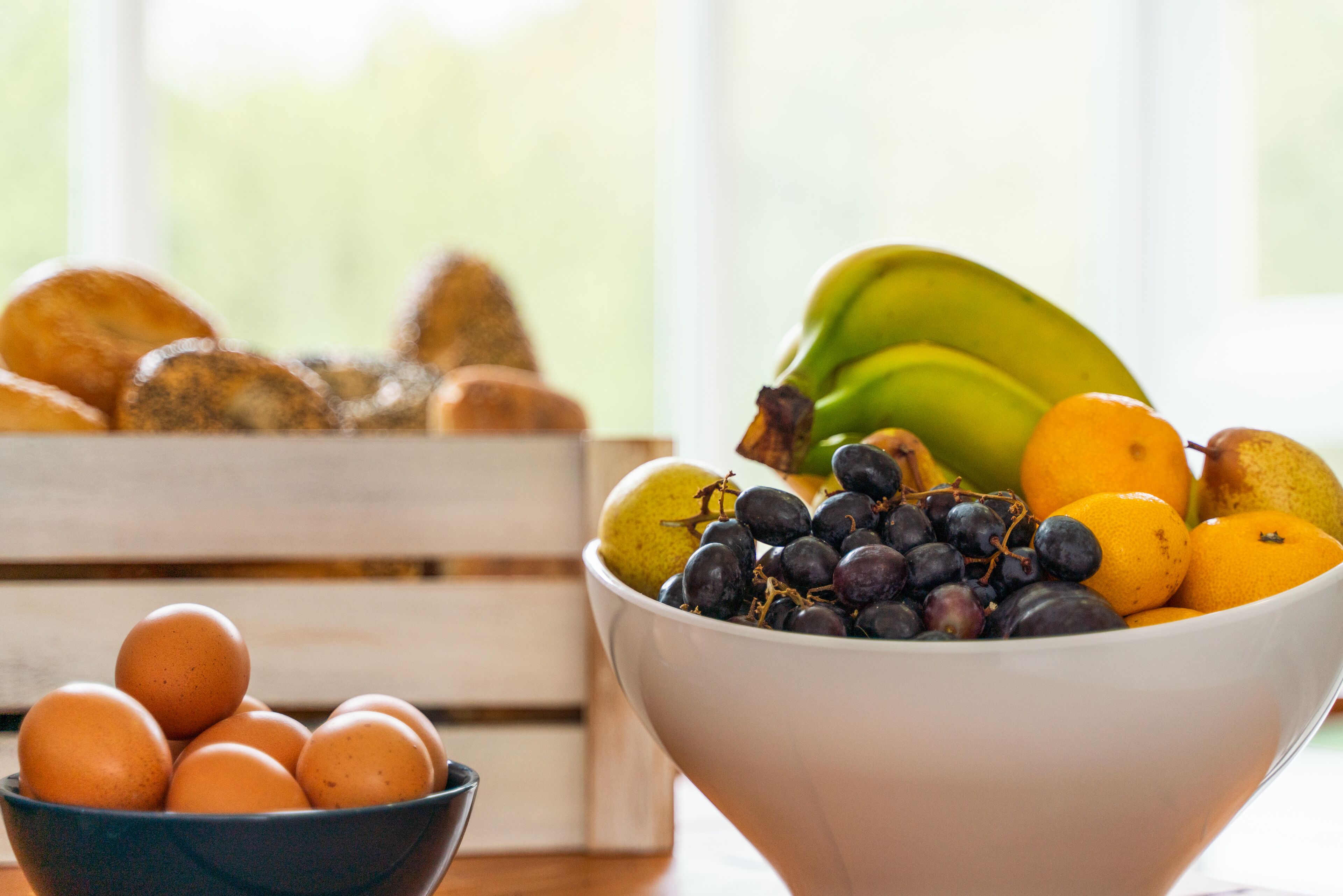 A bowl of fruit and eggs on a table.