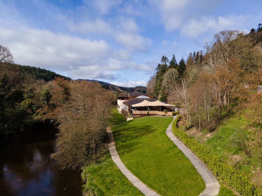 A riverside property with a pathway leading to a building with a large porch.