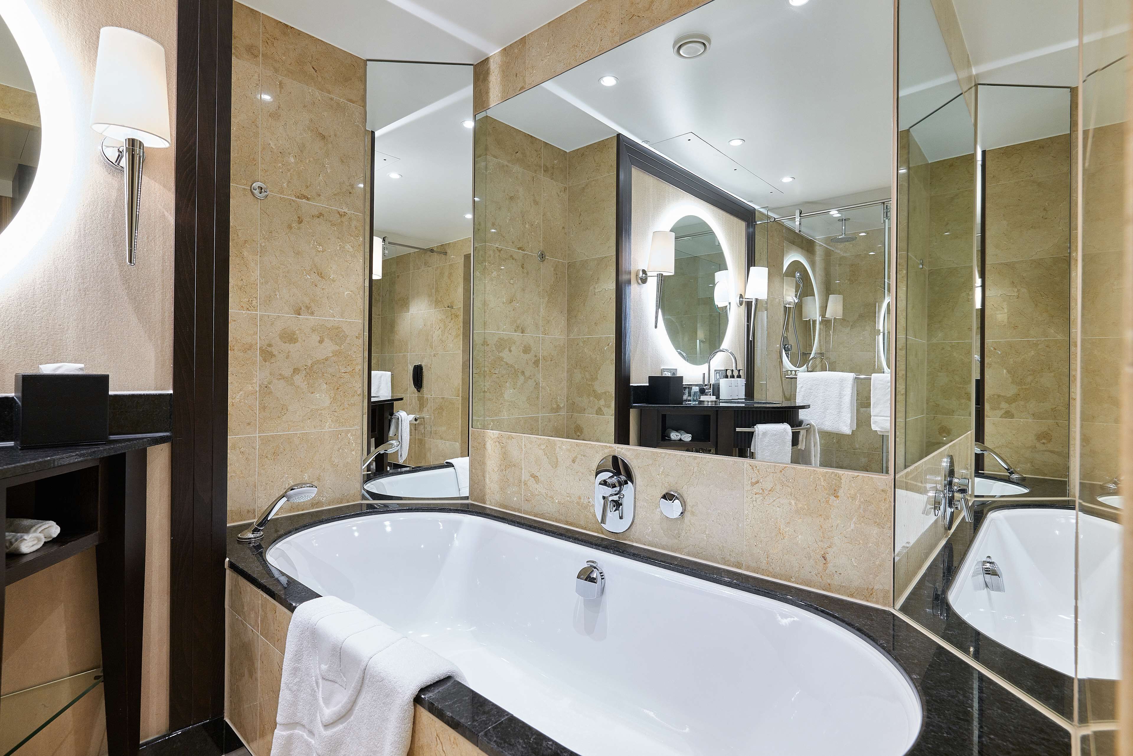 A modern bathroom with a large bathtub, two sinks, and a vanity with a mirror.