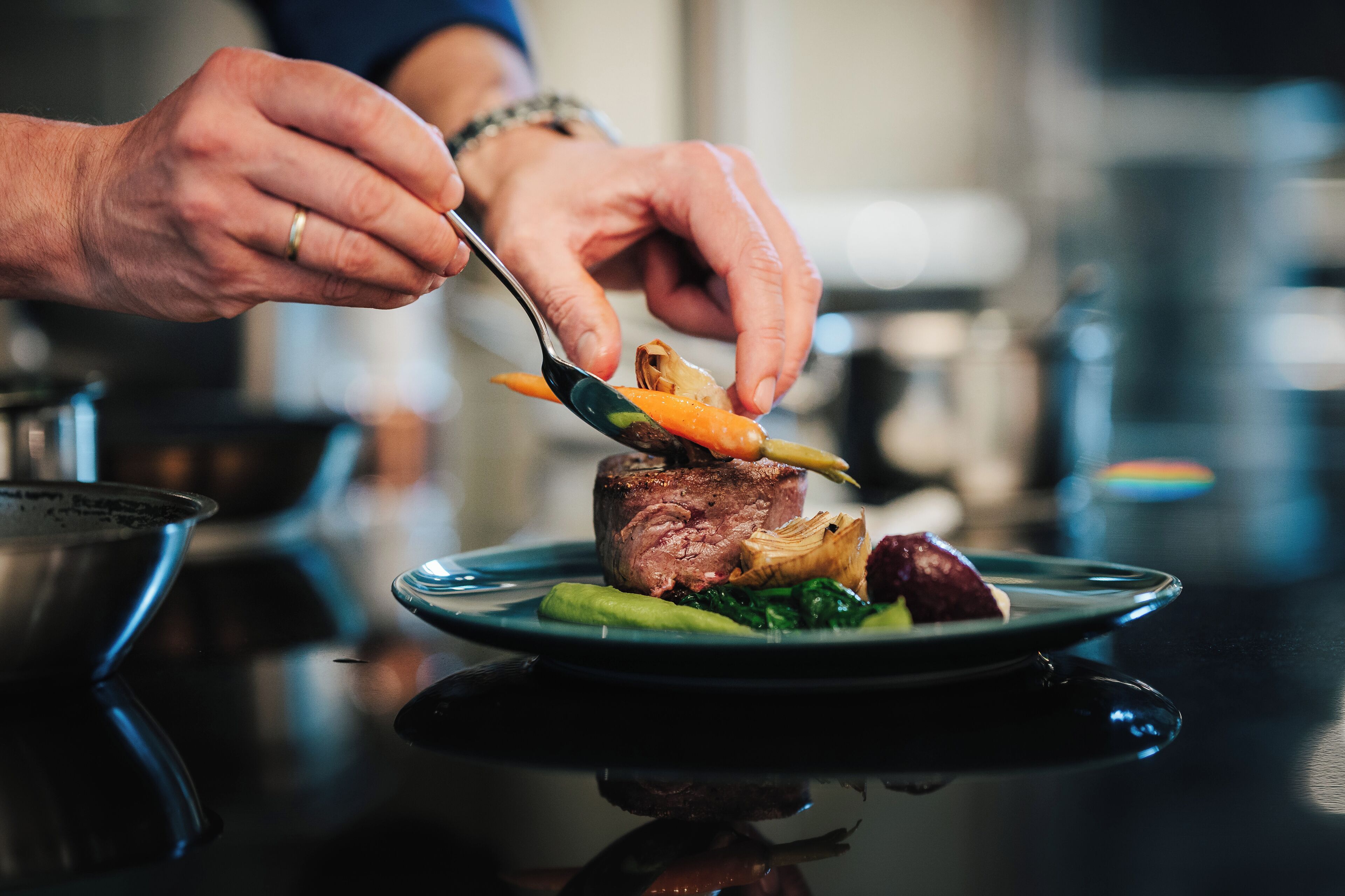 Una persona sirve un plato con carne y verduras.