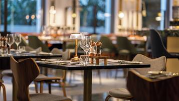 A restaurant interior with tables set for dining, chairs, and a lamp on the table.