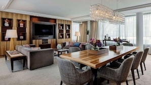 A modern living room with a large flat-screen TV, comfortable seating, a dining area with a wooden table and chairs, and a decorative chandelier. - Hotel Kö59 Düsseldorf - Member of Hommage Luxury Hotels Collection (Düsseldorf)