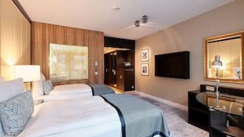 A hotel room with two beds, a TV, a desk with a mirror, and a window with blinds.