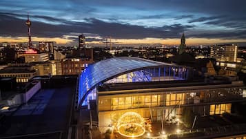 A modern building with a curved glass facade and a spherical light installation on the ground level.