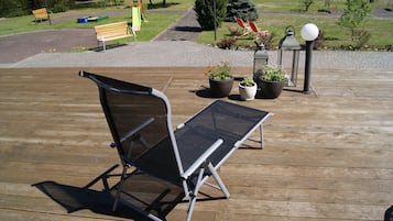 Una terraza de madera con una silla plegable y plantas en macetas.