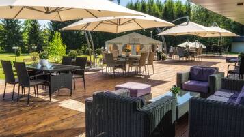 Un patio al aire libre con mobiliario de mimbre, sombrillas grandes y una mesa de comedor.