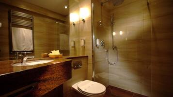 Un baño moderno con lavamanos de granito, inodoro y cabina de ducha con paredes de vidrio.